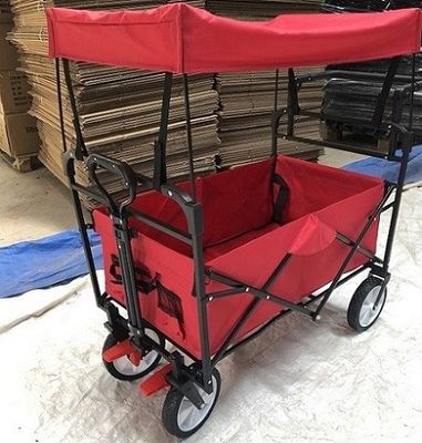 Os carros dobráveis do carro dobrável vermelho do vagão com rodas cobrem o punho do impulso